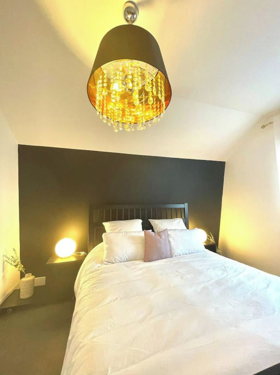 Une chambre à coucher avec un grand lit, une tête de lit sombre et un lustre.