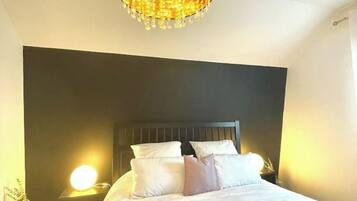 Une chambre à coucher avec un grand lit, une tête de lit sombre et un lustre.