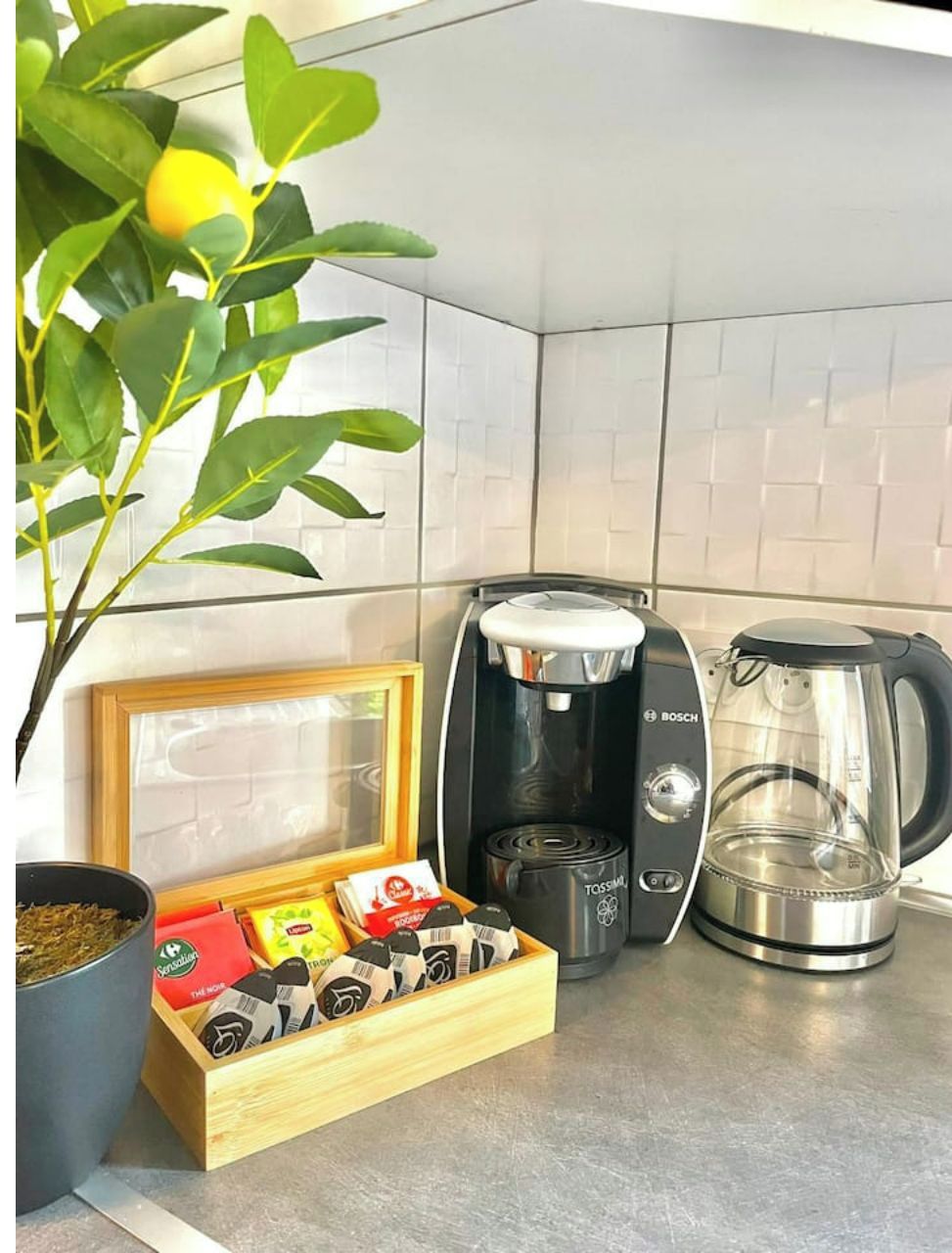 A kitchen with a Bosch coffee maker, a glass coffee pot, and a wooden box of coffee pods.