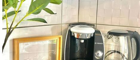 Una cocina con una cafetera Bosch, una jarra de vidrio para café y una caja de madera con cápsulas de café.