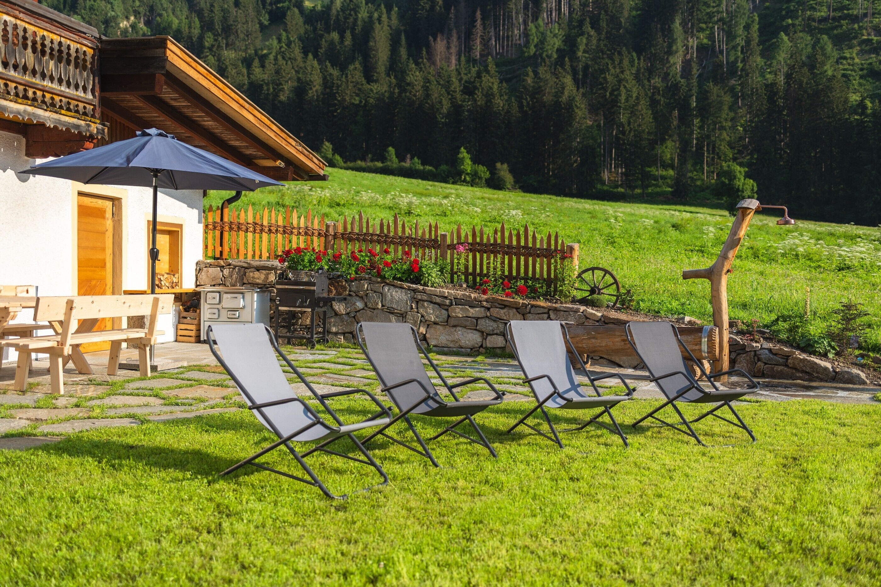 Eine Chalet mit Sitzgelegenheit im Freien, einem Holzzaun und einer Steinmauer.