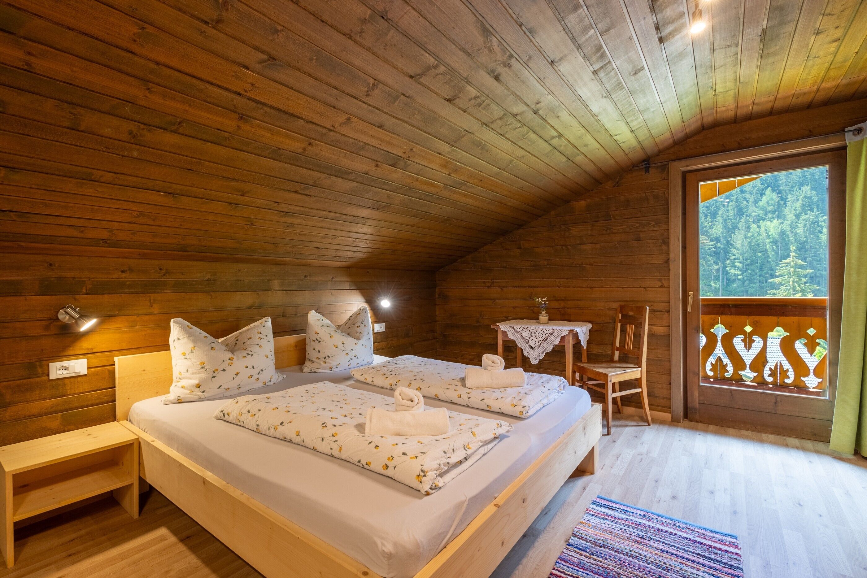 Une chambre dans un chalet en bois, avec deux lits, une petite table et une chaise.