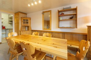 Uma mesa de jantar de madeira com cadeiras, um espelho e prateleiras com objetos.