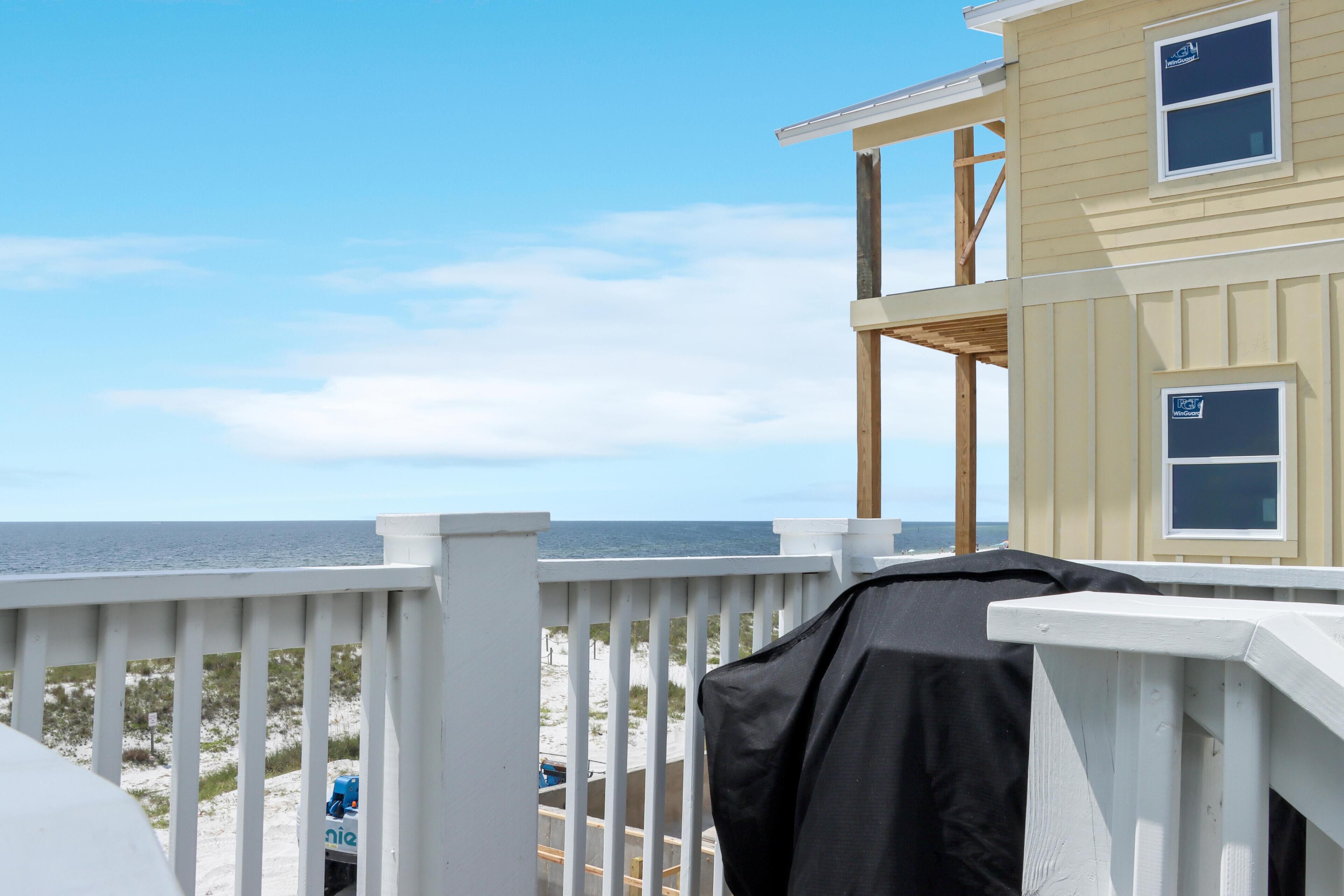 A beach house with a balcony overlooking the ocean.