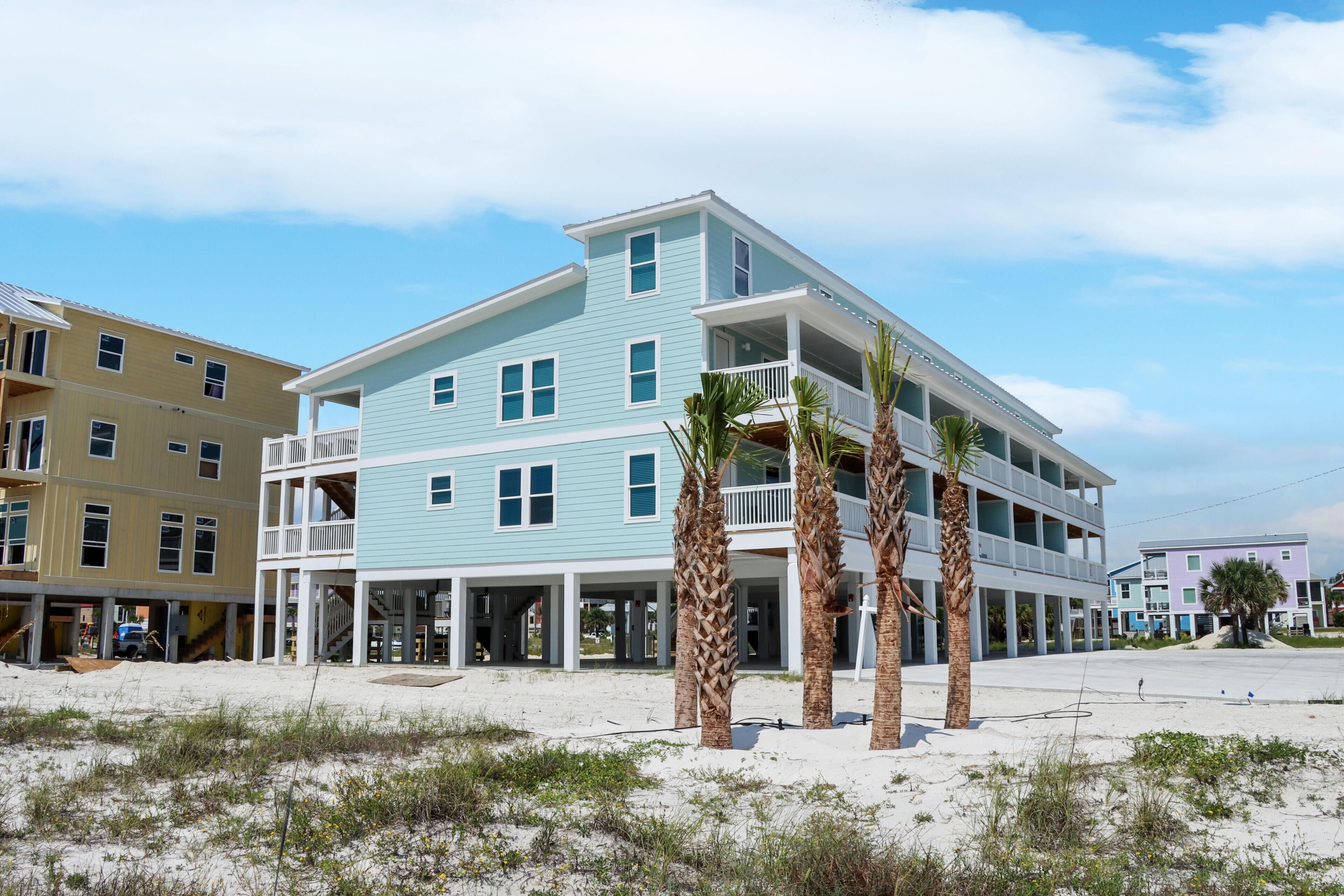 A multi-story beachfront hotel with balconies and a sandy beach in front.