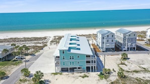 Ein Strandhotel mit mehreren Gebäuden, einem Sandstrand und dem Meer im Hintergrund.