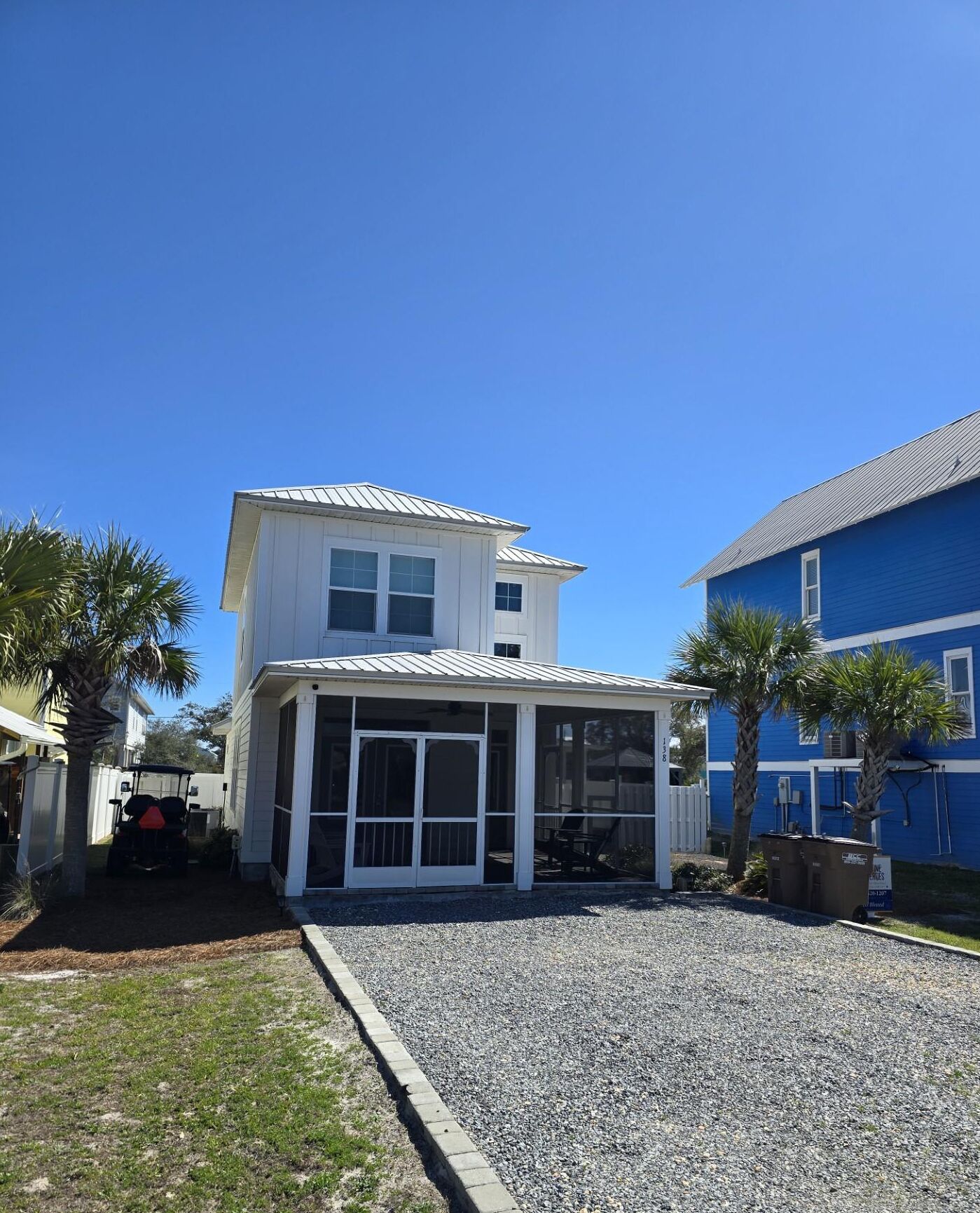 A two-story house with a covered patio and a gravel driveway.