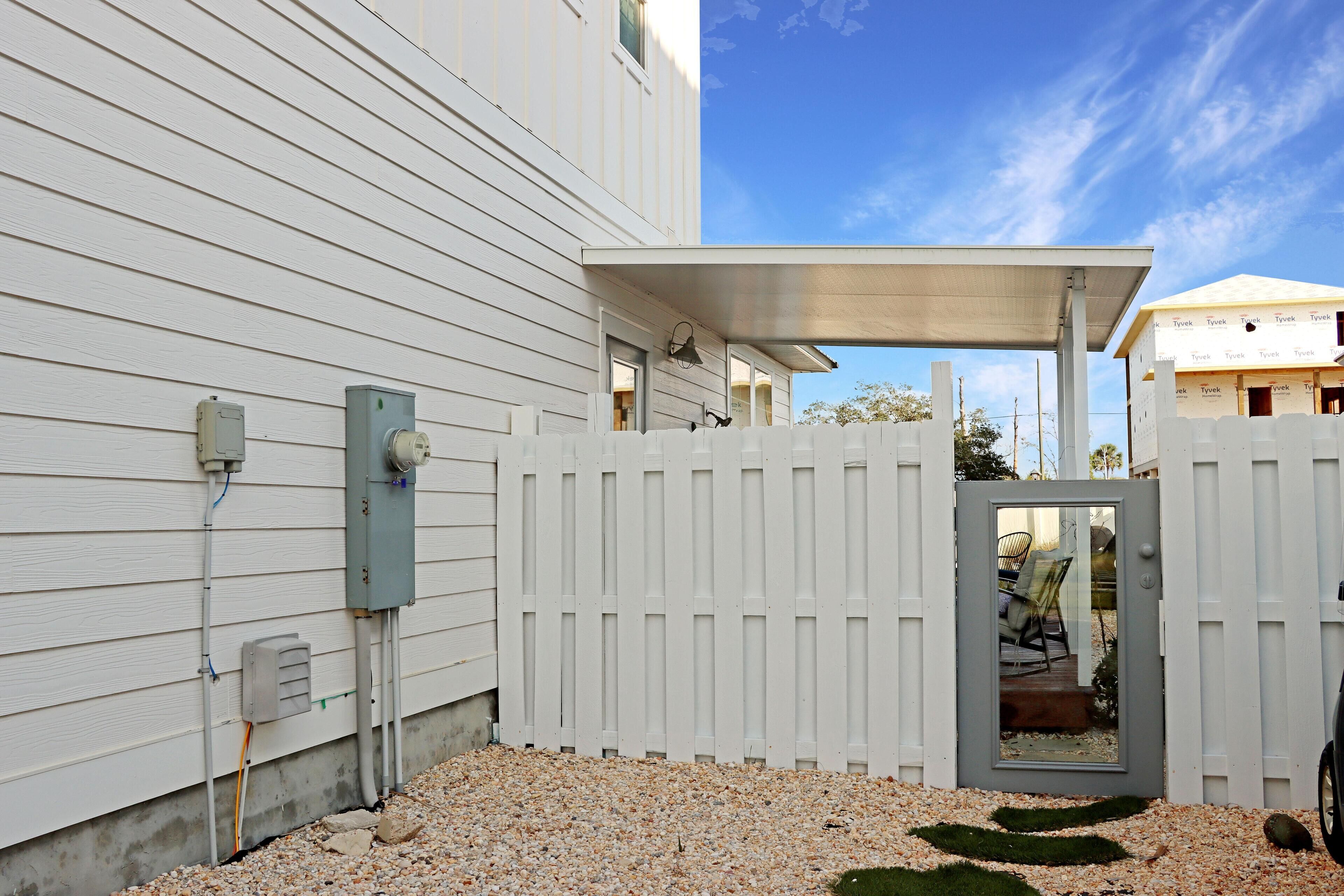 A white house with a gravel driveway and a white fence.