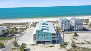 Ein Strandhotel mit mehreren Gebäuden, einem Sandstrand und dem Meer im Hintergrund.