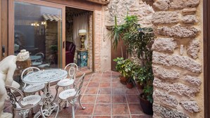 A courtyard with a glass door, a round table with chairs, potted plants, and a stone wall. - Holiday Home 'Siglo 16 Denia' with Private Terrace, Wi-Fi and Air Conditioning (Denia)