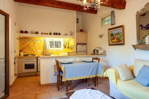 Cozinha compacta com área de refeições, sofá e um quadro na parede.