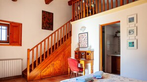 A bedroom with a wooden staircase, a desk with a chair, a bed with a floral bedspread, and a wall with framed pictures. - Holiday Apartment "Les Cigales" with Mountain View, Private Garden & Wi-Fi (Ceyreste)