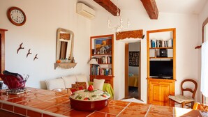 Ein gemütliches Wohnzimmer mit Fliesenboden, einer Holzregal und einem Essbereich mit Tisch.