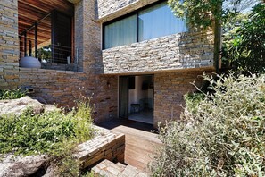 Un bâtiment moderne avec des murs en pierre, une terrasse en bois et une grande fenêtre.