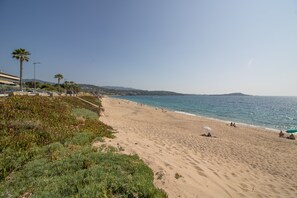 Ein Strand mit blauem Himmel, Palmen und einem fernen Berg.