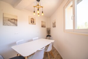 Ein Essbereich mit weißem Tisch und Stühlen, einer Chandelier und Wandkunst.