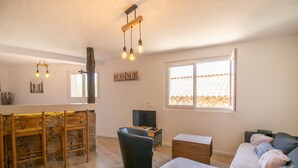 Ein Wohnzimmer mit Sofa, Fernseher, Holztisch und Steinwand.