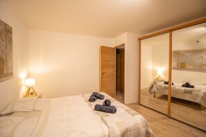 Ein Schlafzimmer mit Bett, Nachttisch, Spiegel und Kleiderschrank.