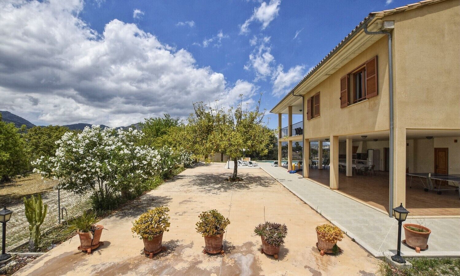 A building with a covered outdoor area, potted plants, and a clear sky.