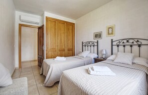 Un dormitorio con dos camas, un armario de madera, una mesita de noche y un cuadro enmarcado en la pared.
