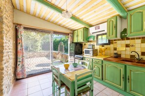Une cuisine avec des meubles de couleur verte, un four à micro-ondes et un évier.