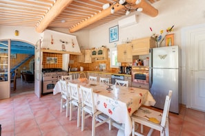 A kitchen with wooden beams, a dining table with floral tablecloth, and a refrigerator with a butterfly design.