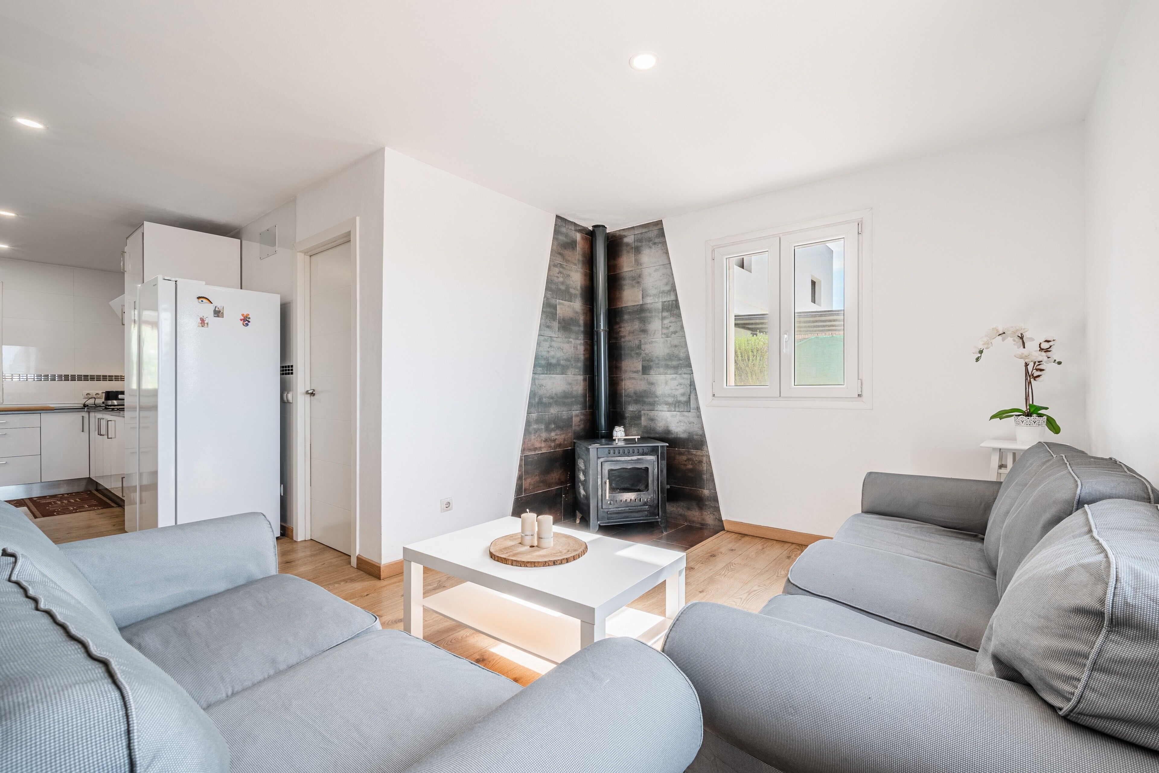 A modern living room with a grey sofa, a white coffee table, and a fireplace.