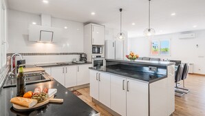 A modern kitchen with white cabinetry, a black countertop, and a central island.