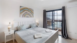 A bedroom with a bed, bedside tables, a nightstand, a window with curtains, and a view of the outside. - Casa Otoño – Holiday Home with Sea View, Private Terrace, and Wi-Fi (La Lajita)