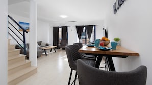 A modern interior with a staircase, a dining area with a table and chairs, and a living space with a sofa and a coffee table. - Casa Otoño – Holiday Home with Sea View, Private Terrace, and Wi-Fi (La Lajita)