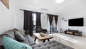A modern living room with a sofa, armchair, and a flat-screen TV. - Casa Otoño – Holiday Home with Sea View, Private Terrace, and Wi-Fi (La Lajita)