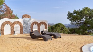 A poolside area with lounge chairs and a stone-tiled floor, surrounded by decorative walls and a view of the landscape. - Holiday Home 'Tower House' with Sea View, Wi-Fi and Air Conditioning (Competa)