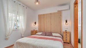 A bedroom with a bed, wooden headboard, bedside tables, and a window with curtains. - Holiday Home 'Tower House' with Sea View, Wi-Fi and Air Conditioning (Competa)