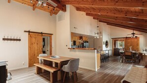 A spacious kitchen with wooden beams, a central island, and a dining area with a bench and chairs.