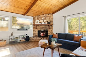 Una sala de estar acogedora con una chimenea de piedra, un ventanal con vistas panorámicas y un rincón de estar cómodo.