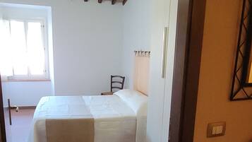 A room with a bed, a chair, a window, and a door.