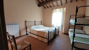Un dormitorio con una cama individual, una silla, un radiador y una ventana con cortinas.