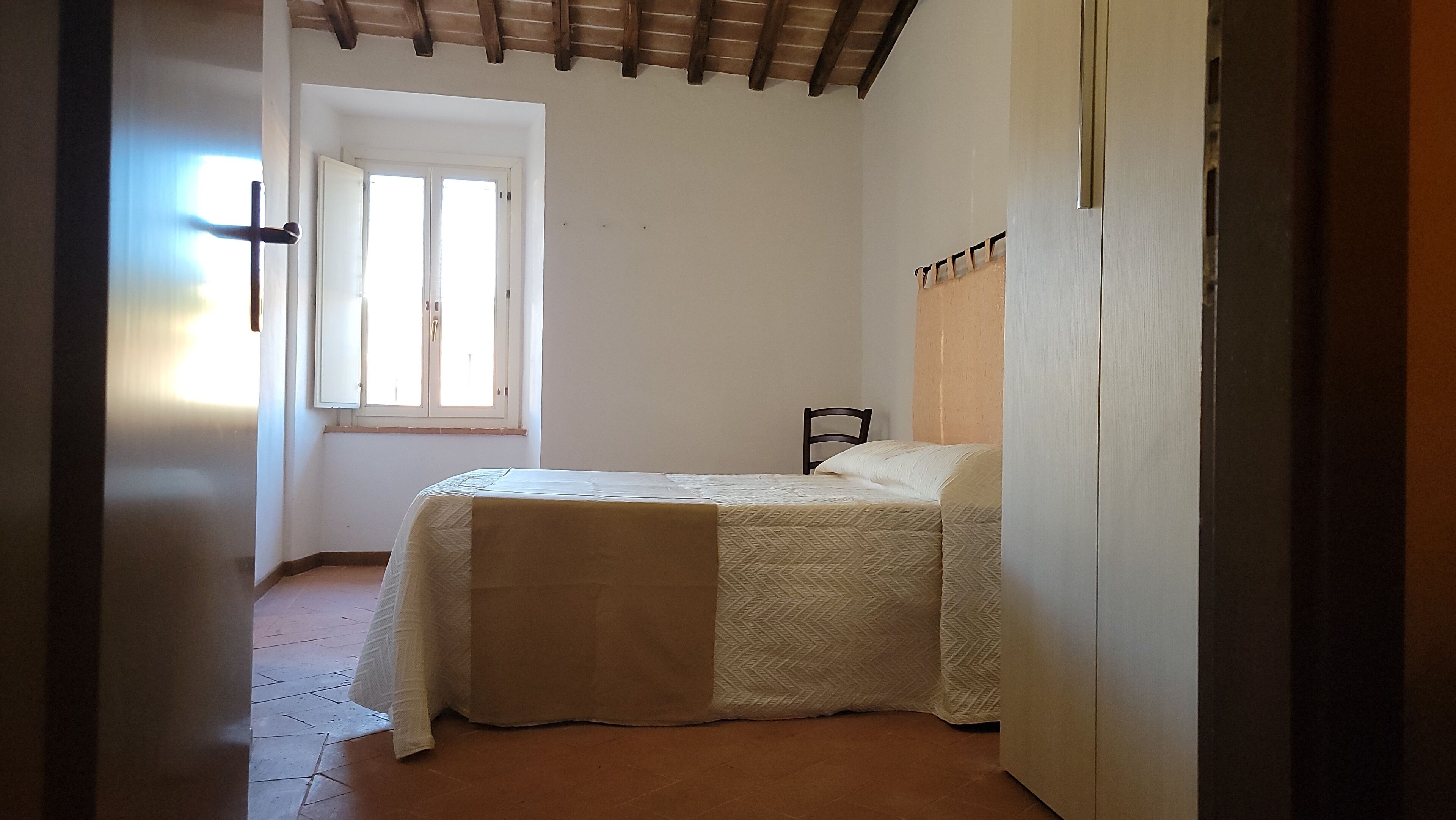 Un dormitorio con cama, ventana y puerta.