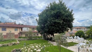 Un jardín con un sendero de piedra, un árbol grande y mobiliario exterior.