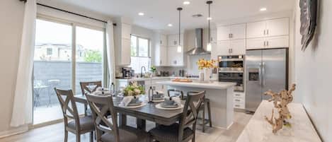 A modern kitchen with white cabinets, a central island, and stainless steel appliances.