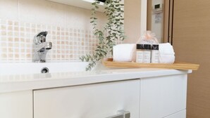 A bathroom with a white sink, a mirror, and a shelf with toiletries.
