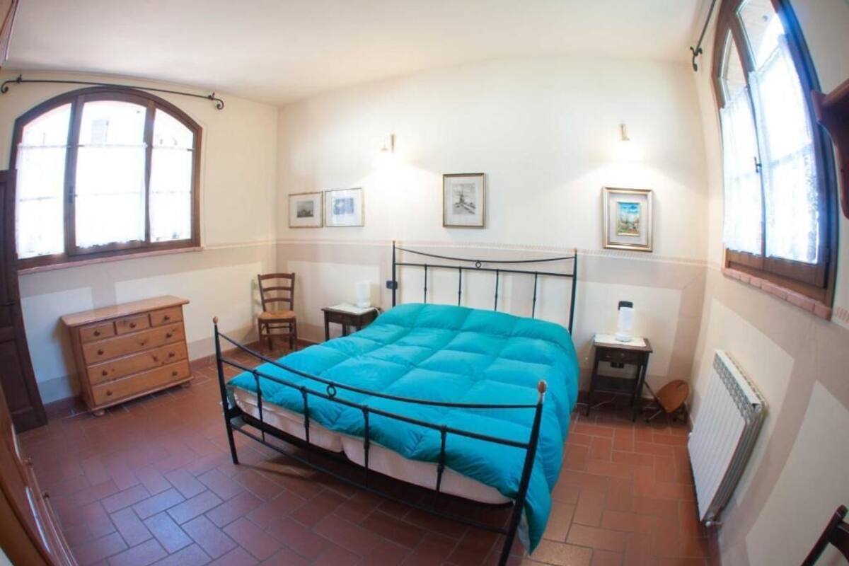 Un dormitorio con cama, cómoda, silla, mesita de noche y dos cuadros en la pared.