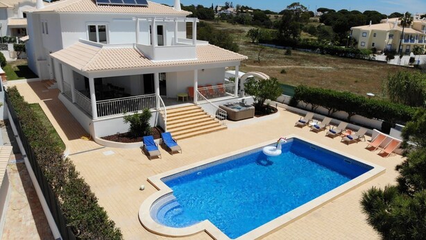 Une maison à deux étages avec une piscine, un espace salon extérieur et un jacuzzi.