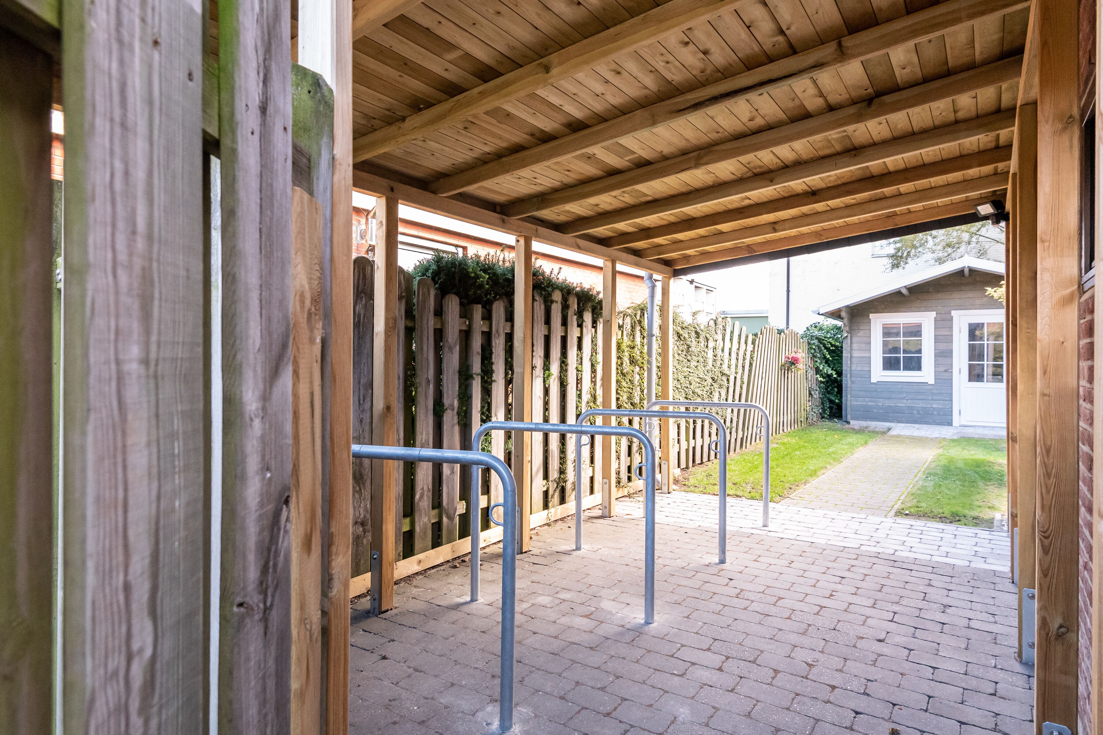 Un espace extérieur abrité, doté de rampes métalliques et d’une clôture en bois.