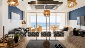 A modern kitchen with a central island, overhead ventilation, and a view of the sea.