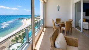 A balcony with a view of the ocean, wicker furniture, and a flat-screen TV.
