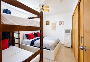A bunk bed room with a ceiling fan, a desk, and a wardrobe.