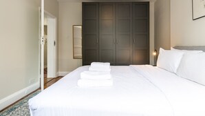 A bedroom with a bed, a wardrobe, a mirror, and a door.