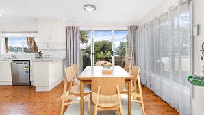 Une cuisine moderne avec des meubles blancs, un lave-vaisselle intégré et une fenêtre donnant sur un jardin.