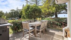 Une terrasse extérieure avec une table et des chaises en bois, entourée de verdure et offrant une vue sur un lac.